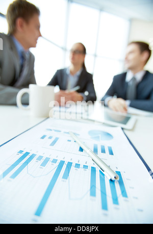 Vertical shot of a business team being on a meeting, focus on financial report in the foreground Stock Photo