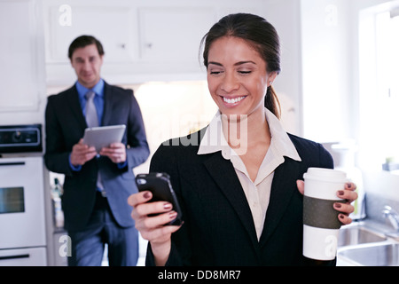 Mixed race businesswoman using tablet computer in kitchen Stock Photo