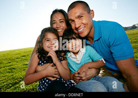 Family smiling together in field Stock Photo