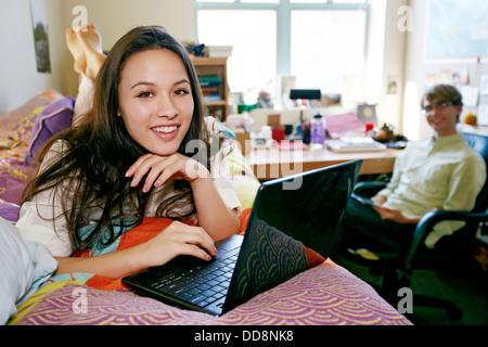 Mixed race college student using laptop in dorm Stock Photo