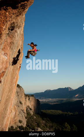 Side view of female sport climber. Adult woman is falling down during rock climbing on Turkish coastland. Geikbayiri, Antalya, Turkey, Europe Stock Photo