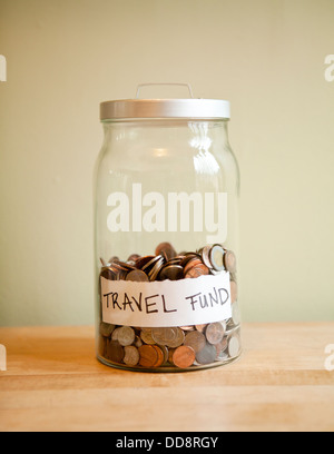 Coins in 'travel fund' jar Stock Photo