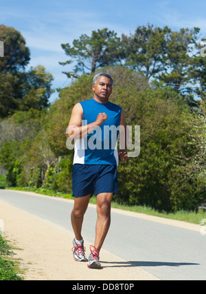Mixed race man running on rural road Stock Photo