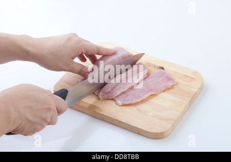housewife cutting pork with knife on a wooden cutting board Stock Photo