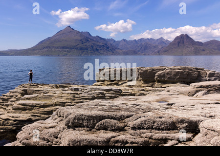 Female holidaymaker admiring view from Elgol over Sea Loch Scavaig to the Black Cuillin mountains, Isle of Skye, Scotland, UK Stock Photo
