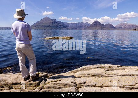 Female holidaymaker admiring view from Elgol over Sea Loch Scavaig to the Black Cuillin mountains, Isle of Skye, Scotland, UK Stock Photo