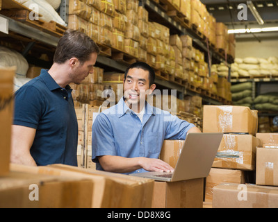Workers using laptop in textile factory Stock Photo