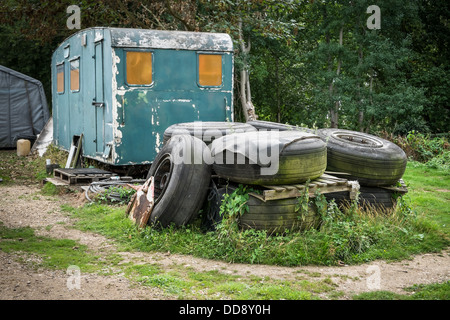 A pile of old tires in front of an abandoned derelict caravan Stock Photo