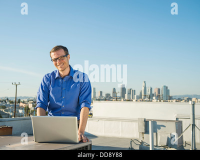Caucasian businessman using laptop on urban rooftop Stock Photo