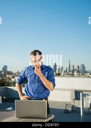 Caucasian businessman using laptop on urban rooftop Stock Photo