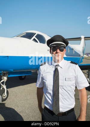 Caucasian pilot by airplane on runway Stock Photo