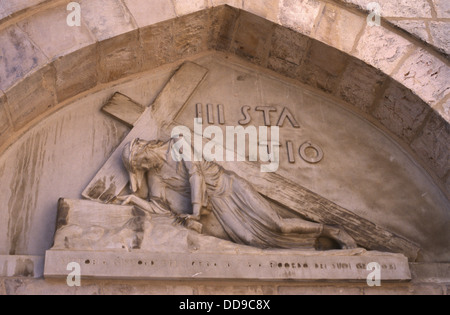 Carved figure of Jesus falling with the cross for the first time at the 3rd station of the cross located at an entrance to the “Hammam es-Sultan”, baths built in 15th century sometimes called the ‘Polish chapel’ as it was renovated with the financial help of the Polish army in the late 40s of the 20th century in Via Dolorosa Old City East Jerusalem Israel. Stock Photo