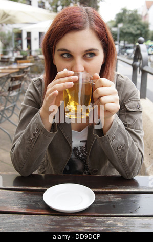Young woman alone drinking in cafe on the terrace with a smartphone in ...
