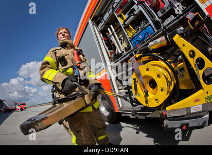 Fire officer of the fire department of Frankfurt airport, Angelina Franz, stands next to a fire engine holding a large cutting tool in her hand on the premises of the Rhine-Main airport in Frankfurt, Germany, 13 August 2013. Franz is one of altogether six women who have joined the fire department at Germany's largest airport. Photo: Frank Rumpenhorst Stock Photo