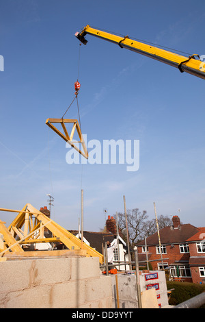 self building house, constructing roof, lifting wooden trusses high over house with crane Stock Photo