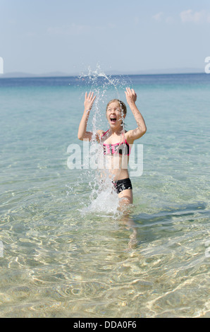 Girl playing in the sea water making water splashes Stock Photo