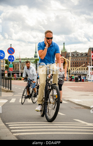 Man using mobile phone while cycling in Stockholm Sweden Stock Photo