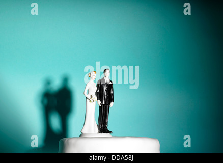 Bride and groom figures on a wedding cake on blue background Stock Photo