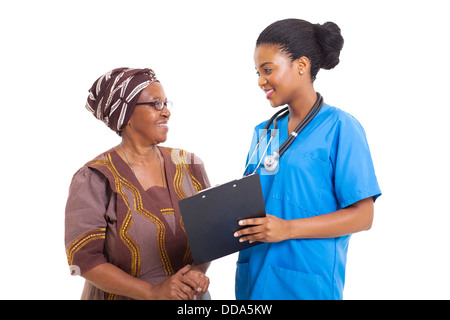 beautiful young African nurse helping senior woman with medical form Stock Photo