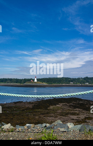 A lighthouse in distance with weathered light blue rope in foreground on the shoreline at Lubec, Maine along Canadian border. Stock Photo