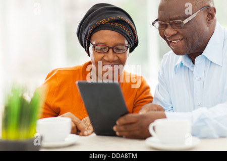 lovely elderly African couple using tablet computer at home Stock Photo
