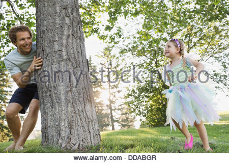 Father and daughter playing hide and seek in park
