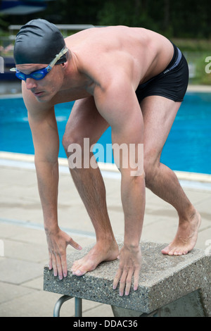 Swimmer on starting block at public swimming pool Stock Photo