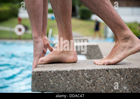 Man standing on starting block at public swimming pool ready to jump Stock Photo