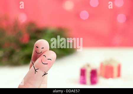 hugging fingers with a holiday background with red, green and presents Stock Photo