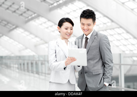 Business colleagues with digital tablet talking in airport lobby Stock Photo