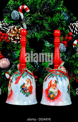 Ceramic Christmas hand bells with wooden handle and Christmas wreath on a black background. Stock Photo