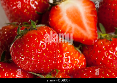 Juicy, sweet, ripe whole strawberries and halved strawberries in a bowl Stock Photo