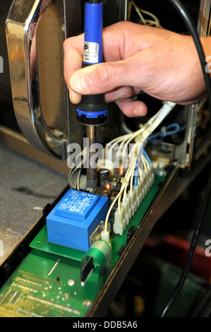 Man working on repairing and reconditioning a microwave cooker Stock Photo