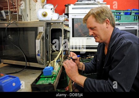 Man working on repairing and reconditioning a microwave cooker Stock Photo