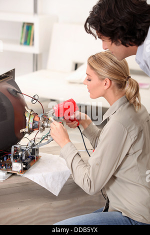 Woman fixing a television Stock Photo