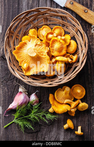 Raw chanterelles in basket on wooden texture Stock Photo