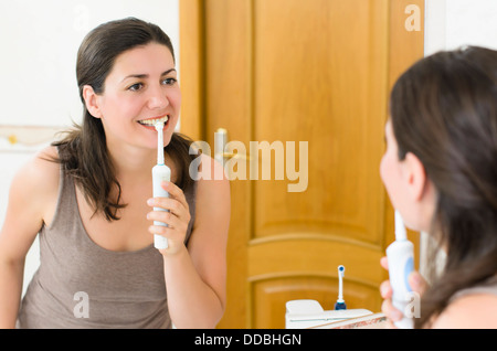 Beautiful woman brushing teeth looking in the mirror Stock Photo