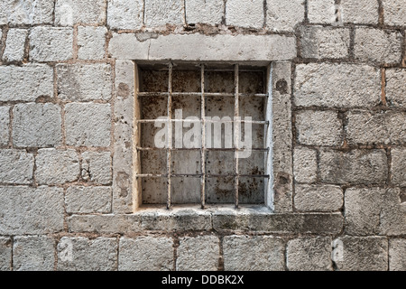 Locked ancient stone prison wall with metal window bars Stock Photo