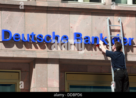 Berlin, Germany, man cleans the logo of Deutsche Bank