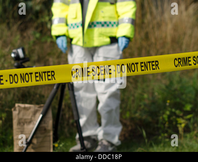 Detective checking for evidence behind a crime scene barrier Stock Photo