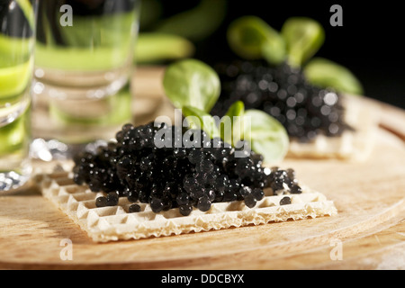 vodka and sandwiches with black caviar on black background Stock Photo