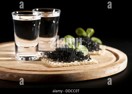 served place setting: vodka and sandwiches with black caviar on black background Stock Photo