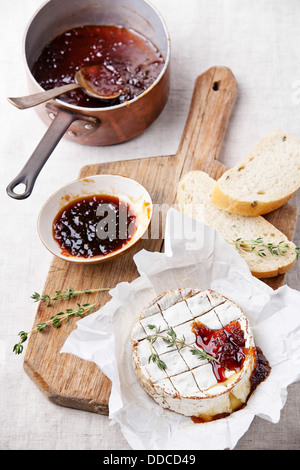 Baked Camembert cheese with thyme and toasted bread on wooden board Stock Photo