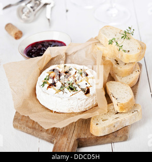 Baked Camembert cheese with thyme and toasted bread on wooden board Stock Photo