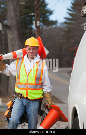 Communications worker moving traffic cones around his truck Stock Photo