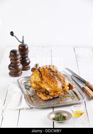 Whole roasted chicken on white wooden background