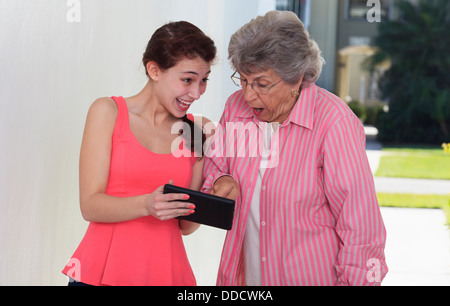 Senior woman smiling and her granddaughter using a digital tablet Stock Photo