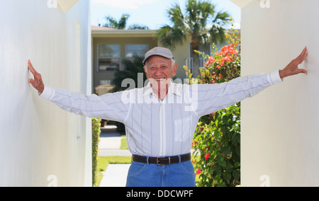 Senior man smiling relaxing in a doorway Stock Photo