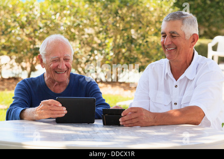 Elderly father and senior son using electronic gadgets Stock Photo