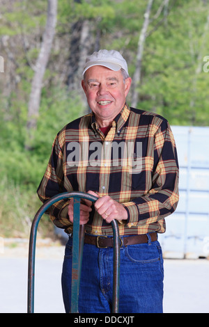 Senior man standing in a warehouse with a hand truck Stock Photo